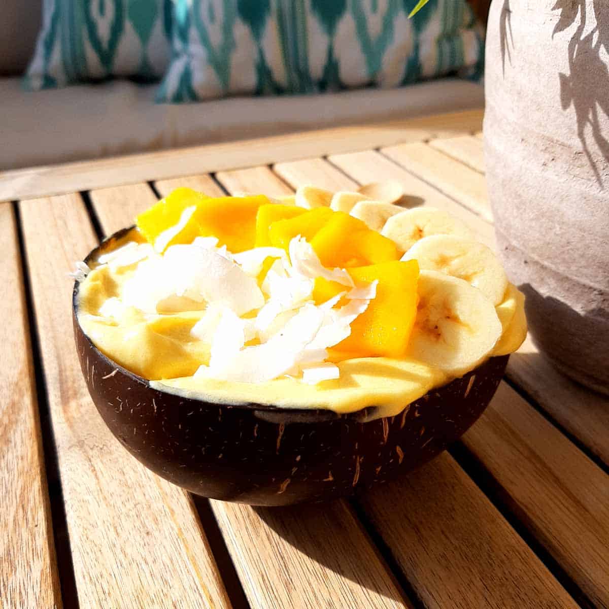 Tropical nice cream in a coconut bowl on a wooden table